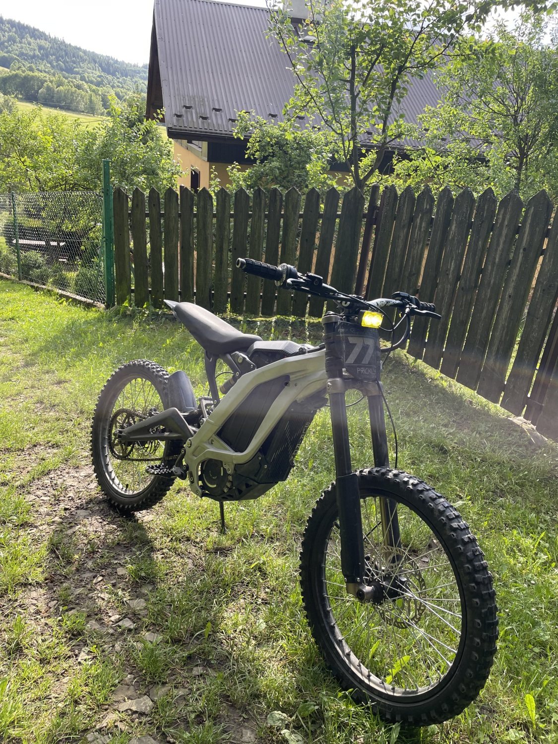 Oliwkowy Sur-Ron Light Bee X przy drewnianym płocie w Beskidach