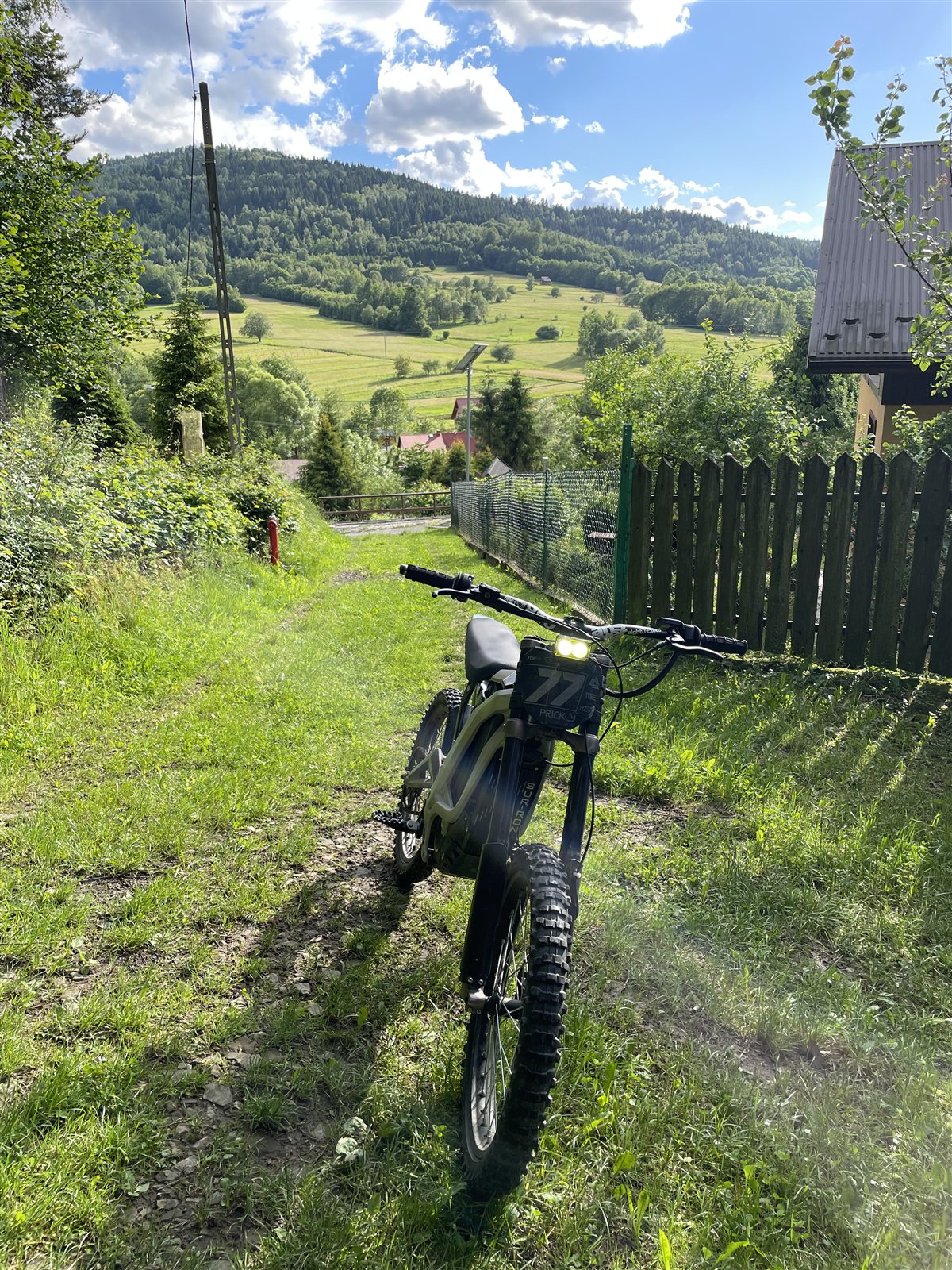 Sur-Ron na górskiej ścieżce z panoramą zielonych wzgórz